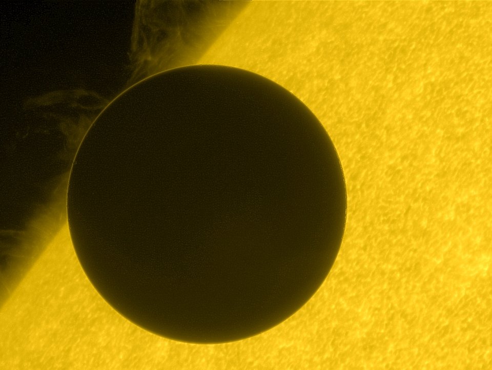 La planète Vénus (sombre) est vue entière en train de passer devant le Soleil (jaune), que l'on ne voit pas en entier. Image de la mission Jaxa/Nasa Hinode. 