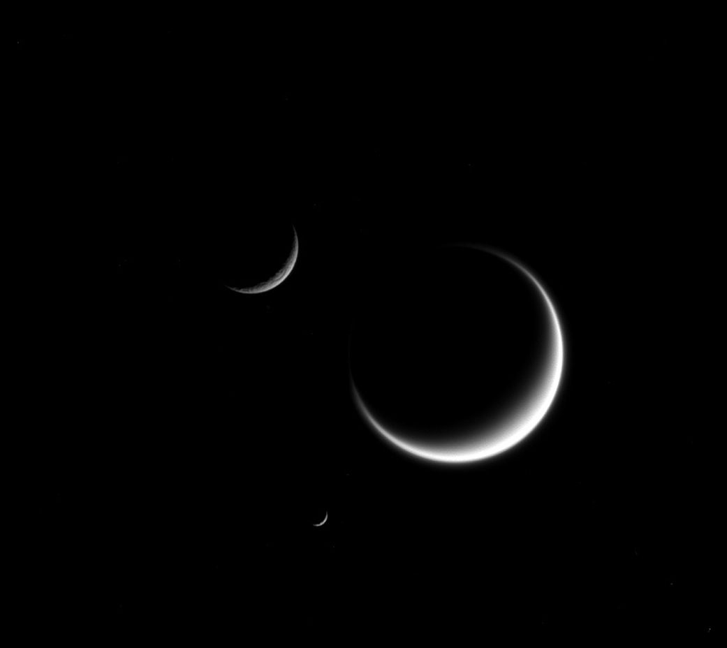 Photo de trois satellites de Saturne : Titan, Mimas et Rhea, montrant chacun une forme de croissant.