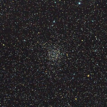 Image de l'amas ouvert NGC7789 dans la constellation de Cassiopée. On voit un fourmillement d'étoiles sur un fond de ciel noir, et au centre un groupement d'étoiles plus dense.