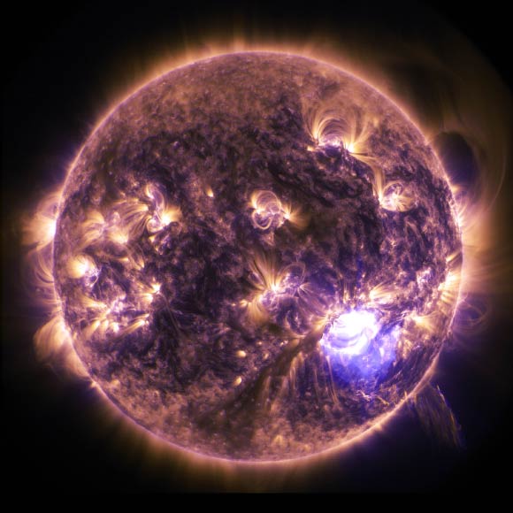 Éruptions solaires vues en UV lointain en décembre 2014 : on voit le Soleil en totalité, en couleurs orange et violet, avec plusieurs éruptions solaires de part et d'autre de la sphère en couleur jaune vif.