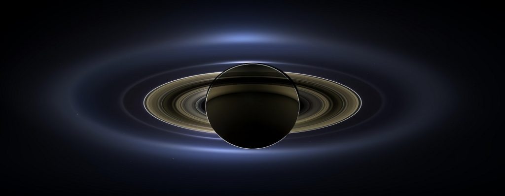 Vue de Saturne par Cassini : on voit la planète par dessous, avec ses anneaux. Le fond est noir et Saturne est en couleurs marron/sombre, avec l'ombre des anneaux en noir. 