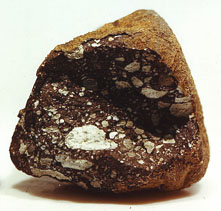 Photo de la première météorite lunaire découverte : sur fond blanc, c'est un caillou aux couleurs marron, qu'on dirait cassé, avec des touches de blanc.