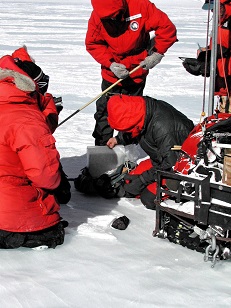 Scientifiques en doudounes rouges et noires sur la banquise, détecteurs de métaux en main, à la recherche de météorites. 