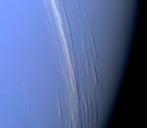 Zoom sur la surface bleue de Neptune où l'on voit des nuages parallèles à l'équateur, dans la très haute atmosphère, dont les ombres se reflètent sur les nuages inférieurs (d'apparence uniforme).