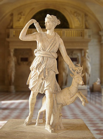 Dans un couloir du musée du Louvre, statue de la déesse Artemis en train de marcher, sa main gauche sur une biche et sa main droite prenant une flèche de son carquois.