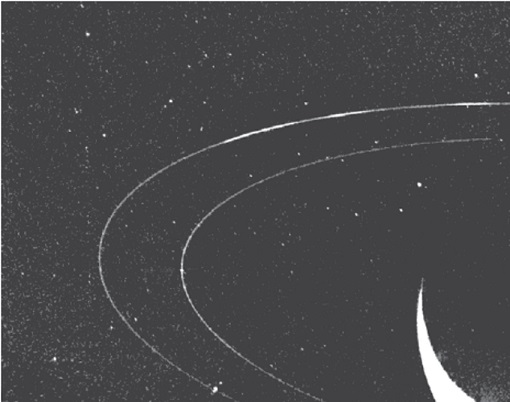 Photo en noir et blanc prise par Voyager 2 de deux anneaux de Neptune. On voit l'anneaux d'Adams en gris et des arcs plus brillants en blanc. 