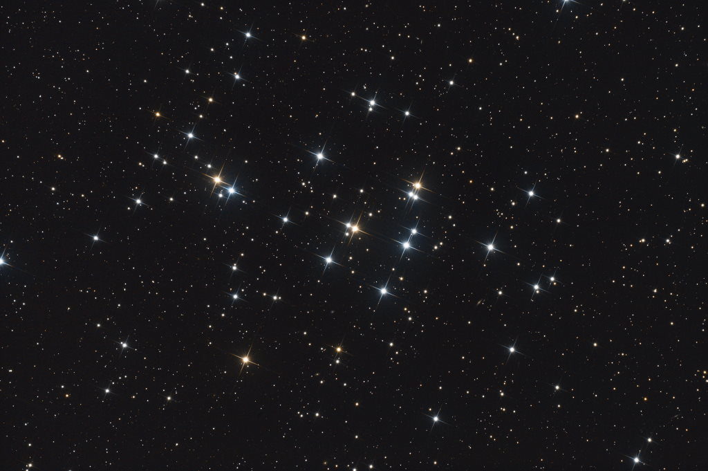 Photo montrant l'amas ouvert M44. On y voit une vingtaine d'étoiles brillantes dont certaines sont bleutées et d'autres orangées. Il y a aussi beaucoup d'étoiles plus faibles.