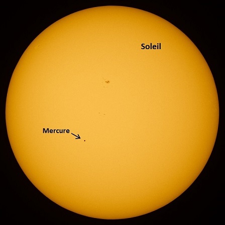 Le Soleil est vu en entier, orange clair sur fond noir, et un petit point noir représente Mercure qui passe devant notre étoile lors de son transit en mai 2016.  