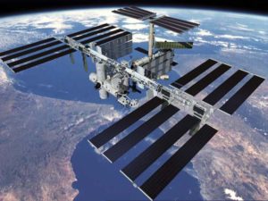 Vue globale de l'ISS avec la Terre en arrière plan et en orbite la station, notamment ses 24 panneaux solaires bien en évidence.