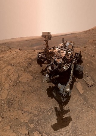 Selfie pris du rover Curiosity par lui-même en octobre 2019 : on y voit le rover sur le sol martien de jour, son ombre sur le sol vers l'avant de la photo.