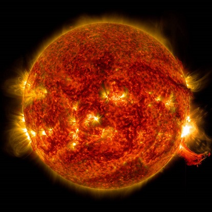 Image sur fond noir du Soleil. On le voit en entier, on distingue une éruption solaire en bas à droite et sur toute la surface rouge orangé du Soleil, des traces d'activité.