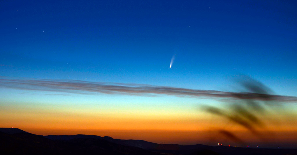 La comète C/2020 F3 (NEOWISE) photographiée au matin du 7 juillet 2020 par Cyril Calvet, depuis le belvédère catalan de Força Real (Pyrénées orientales). On voit la comète s'élever à la verticale au dessus du ciel colorée d'orange à l'horizon.