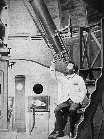 Photo en noir et blanc de la fin du XIXe siècle de l'astronome français Flammarion. Il est assis en bas à droite de l'image, et regarde dans un télescope au-dessus de lui. 