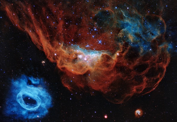 Deux nébuleuses vues par Hubble : une petite bleue en bas à gauche de l'image, et une grande rouge à droite qui évoque un récif corallien.