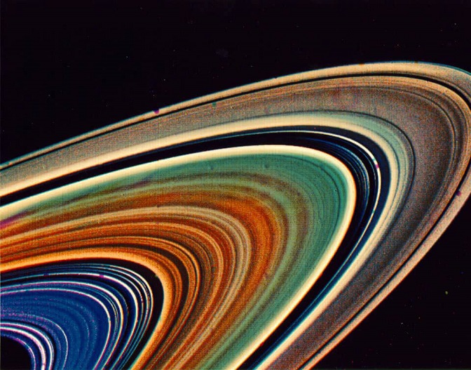 Zoom sur les anneaux de Saturne, dont les couleurs ont été amplifiées : du plus proche du centre de la planète au plus éloigné les anneaux sont de couleur bleu, orangé, vert puis marron jaune.