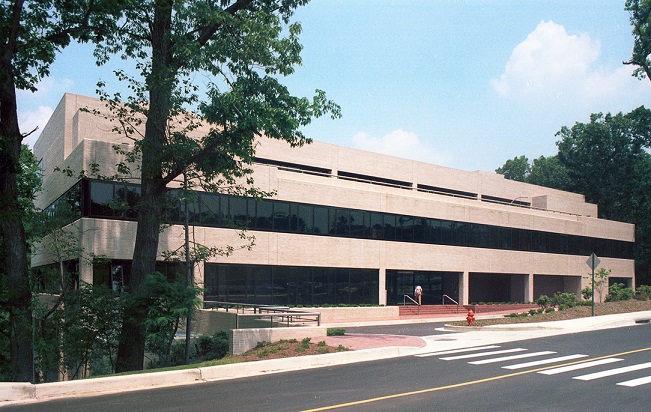 Devanture du Space Telescope Science Institute à Baltimore, dans le Maryland, où est née l'idée du JWST. La façade du bâtiment de deux étages est plutôt en longueur, avec des vitres tout du long, et les murs couleur beige clair.  
