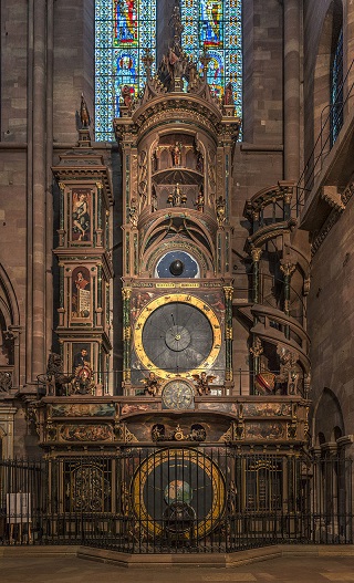 Photo de l'horloge astronomique de Strasbourg. On voit qu'elle est très haute, pourvue de plusieurs cadrans et éléments en pierre et bois. Par endroits, on y observe des peintures bibliques.