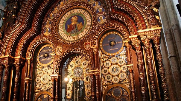 Photo de l'horloge de Beauvais. Ses multiples cadrans et décorations bibliques sont visibles. La couleur majoritaire est le marron, agrémenté de peintures bleutées et de dorures. 