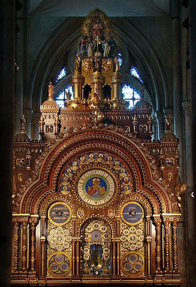 Photo de l'horloge de Beauvais : on la voit s'élever à 12 mètres de haut. Ses multiples cadrans et décorations bibliques sont visibles. La couleur majoritaire est le marron, agrémenté de peintures bleutées et de dorures. 