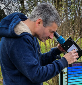 Photo d'Alexandre Piguet regardant dans l'oculaire d'un spectroscope.