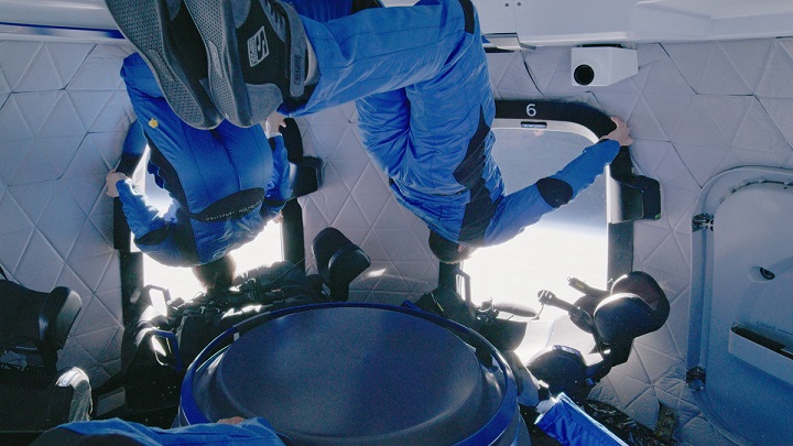 Des touristes de l'espace en apesanteur en combinaison bleu dans la capsule de Blue Origin.