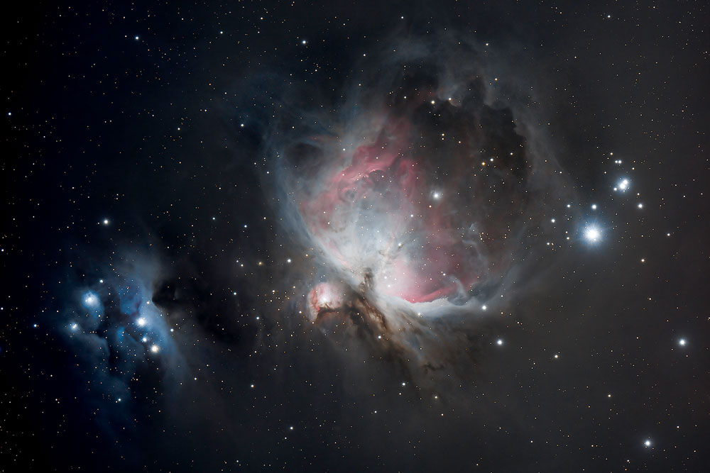 Image de la grande nébuleuse M42 située dans la constellation d'Orion. Sur un fond étoilé, on voit les volutes roses, grises et bleues de la nébuleuse avec de nombreux détails de structure. La nébuleuse ressemble un peu à un oiseau aux aile déployées.