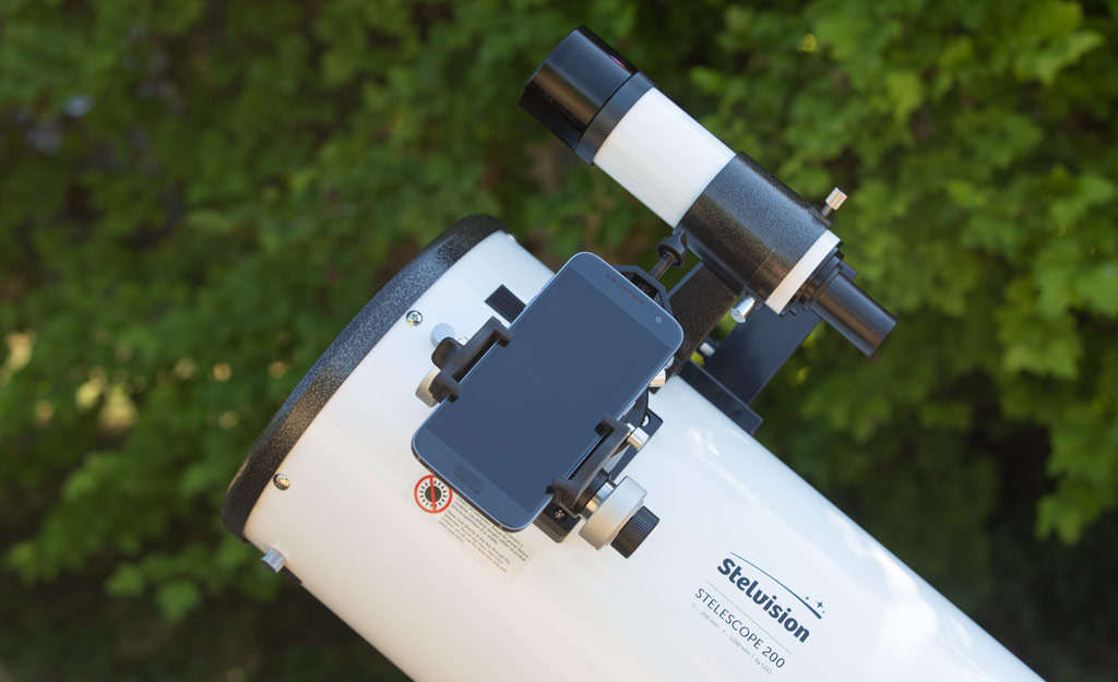 Photo montrant un smartphone fixé sur un télescope à l'aide d'un adaptateur spécifique.