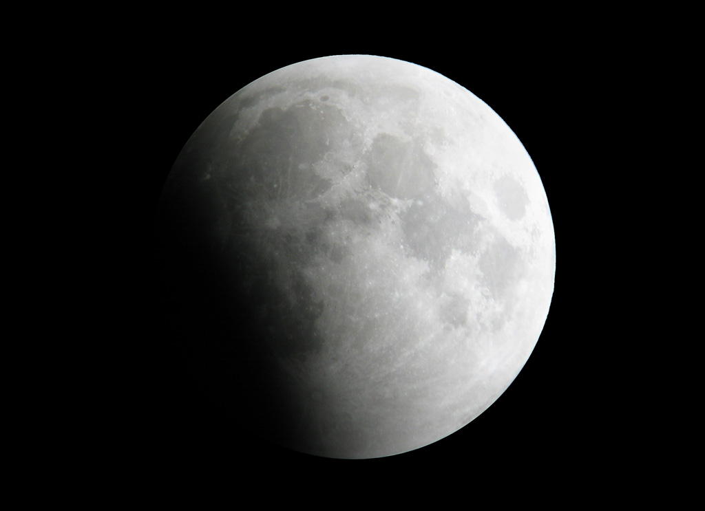 Image montrant la Lune partiellement éclipsée, seule une partie du globe éclairé est assombri et la transition ombre-lumière est progressive.