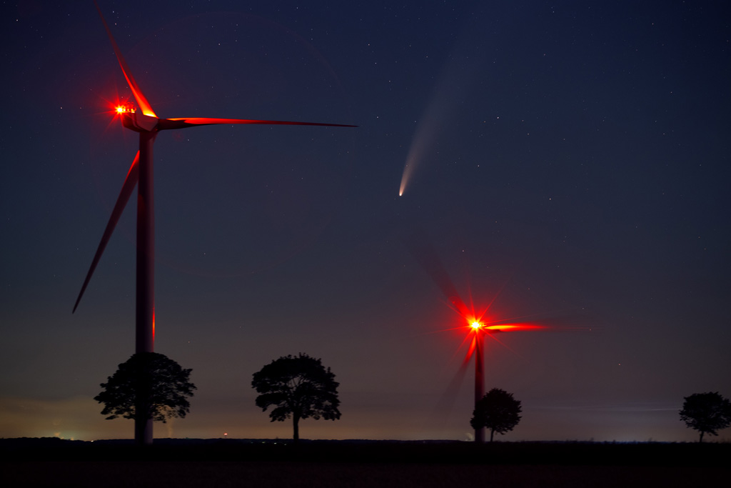 la comète Neowise au crépuscule devant les éoliennes et un paysage de campagne.