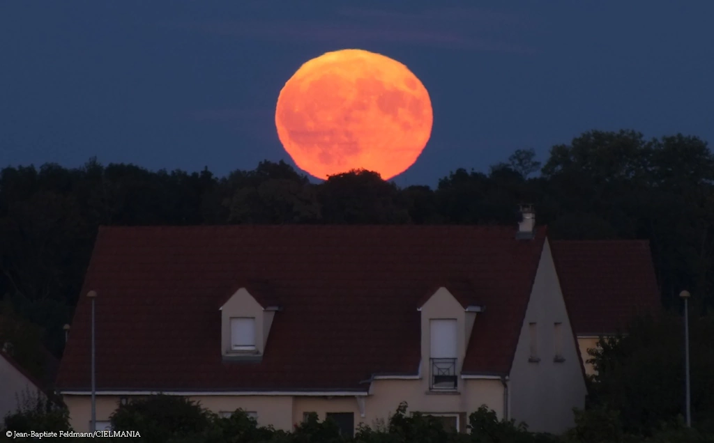 photo de pleine lune très grosse au-dessus d'une maison