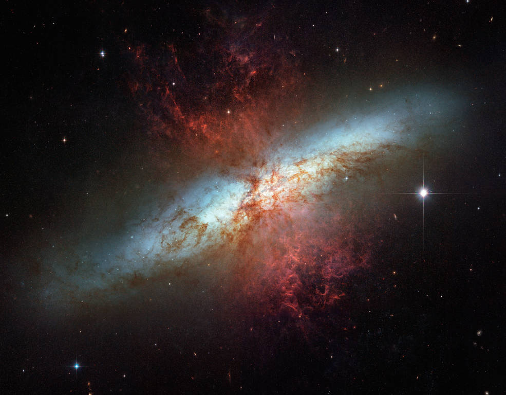 Galaxie starburst à très fort taux de formation d'étoiles vue de côté en couleurs bleu et rouge. 