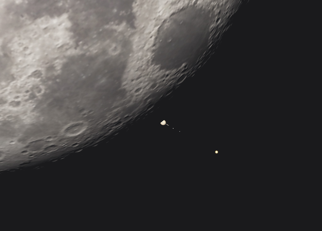 On voit un morceau de Lune (au sud-ouest), le fond de ciel est noir. La planète Saturne est en train de réapparaître de derrière le fin croissant sombre de la Lune. On voit la moitié de la planète entourée de ses anneaux, et aussi trois satellites, dont Titan, le plus lumineux, est le plus éloigné.