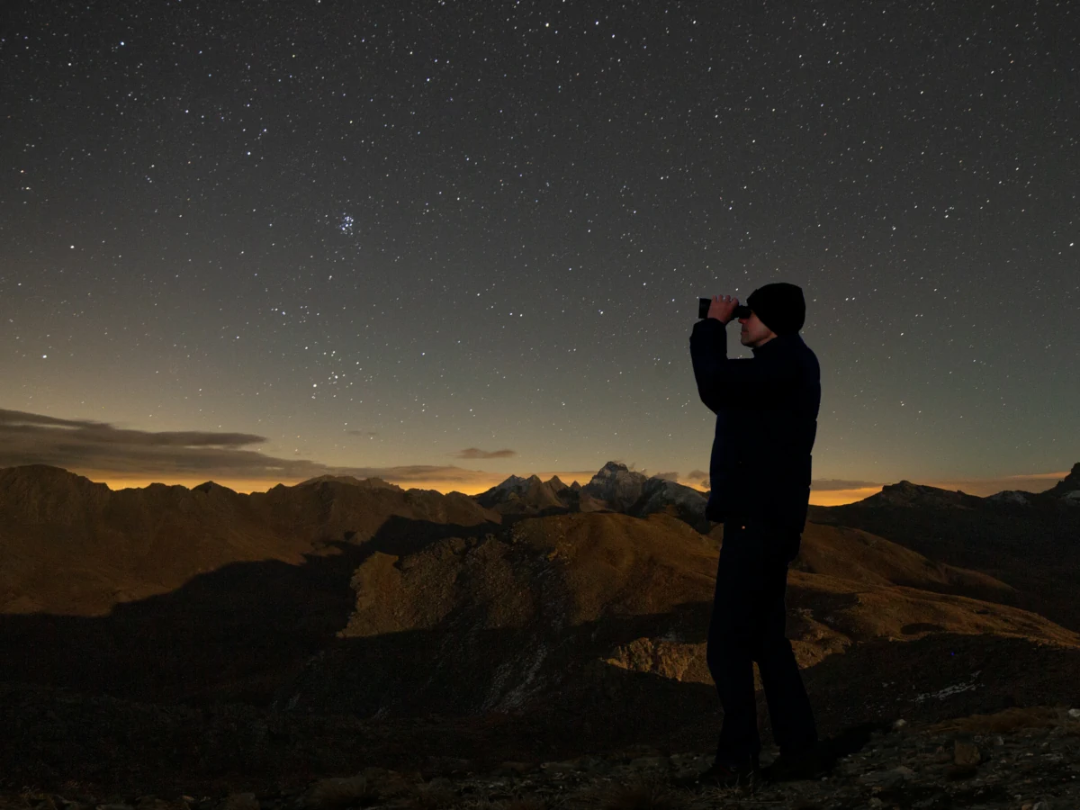 photo d'une personne observant aux jumelles un beau ciel étoilé en montagne