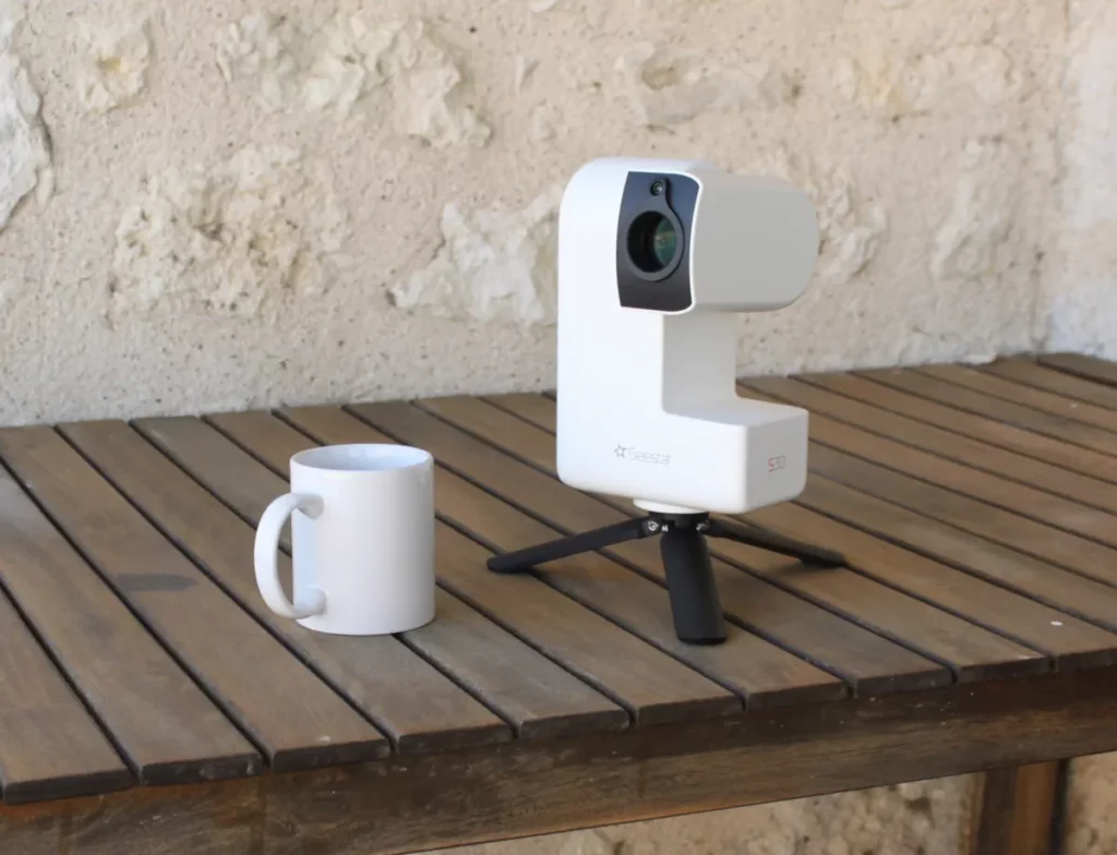 Photo montrant un smart telescope (Seestar 30) posé sur une table avec un mug. Photo : Stelvision.